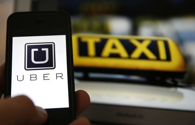 Logo của Uber trên điện thoại thông minh bên cạnh biển hiệu taxi ở Frankfurt, Đức năm 2014. Ảnh: Reuters.