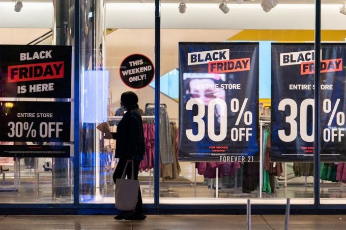 Một người phụ nữ đi ngang qua các biển quảng cáo giảm giá  Black Friday ở Manhattan, New York hôm 26/12. Ảnh: Reuters